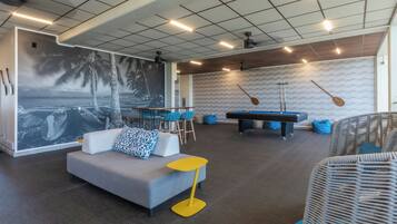 A modern lounge area with a pool table, seating, and a mural.
