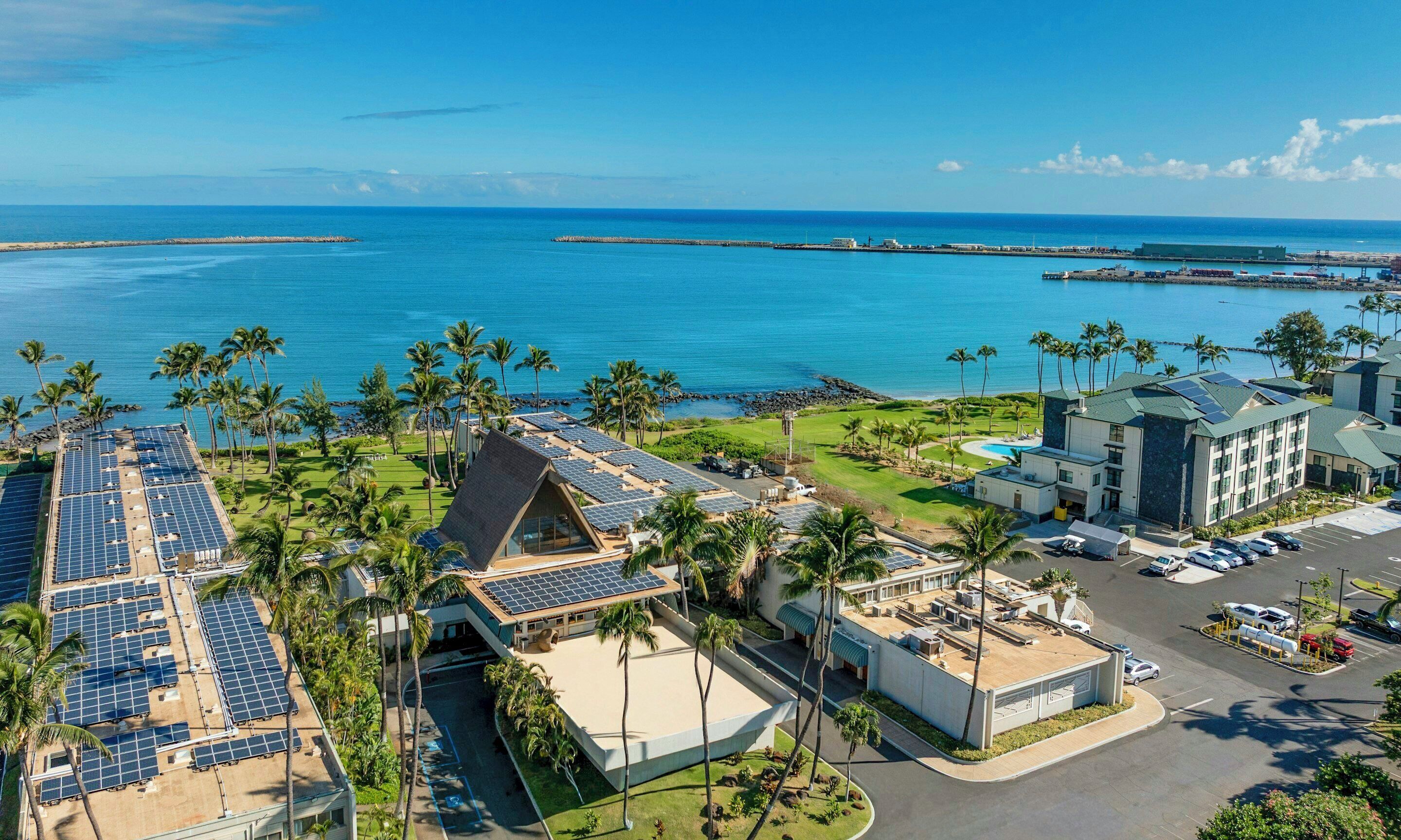 A resort with solar panels, a pool, and a view of the ocean.