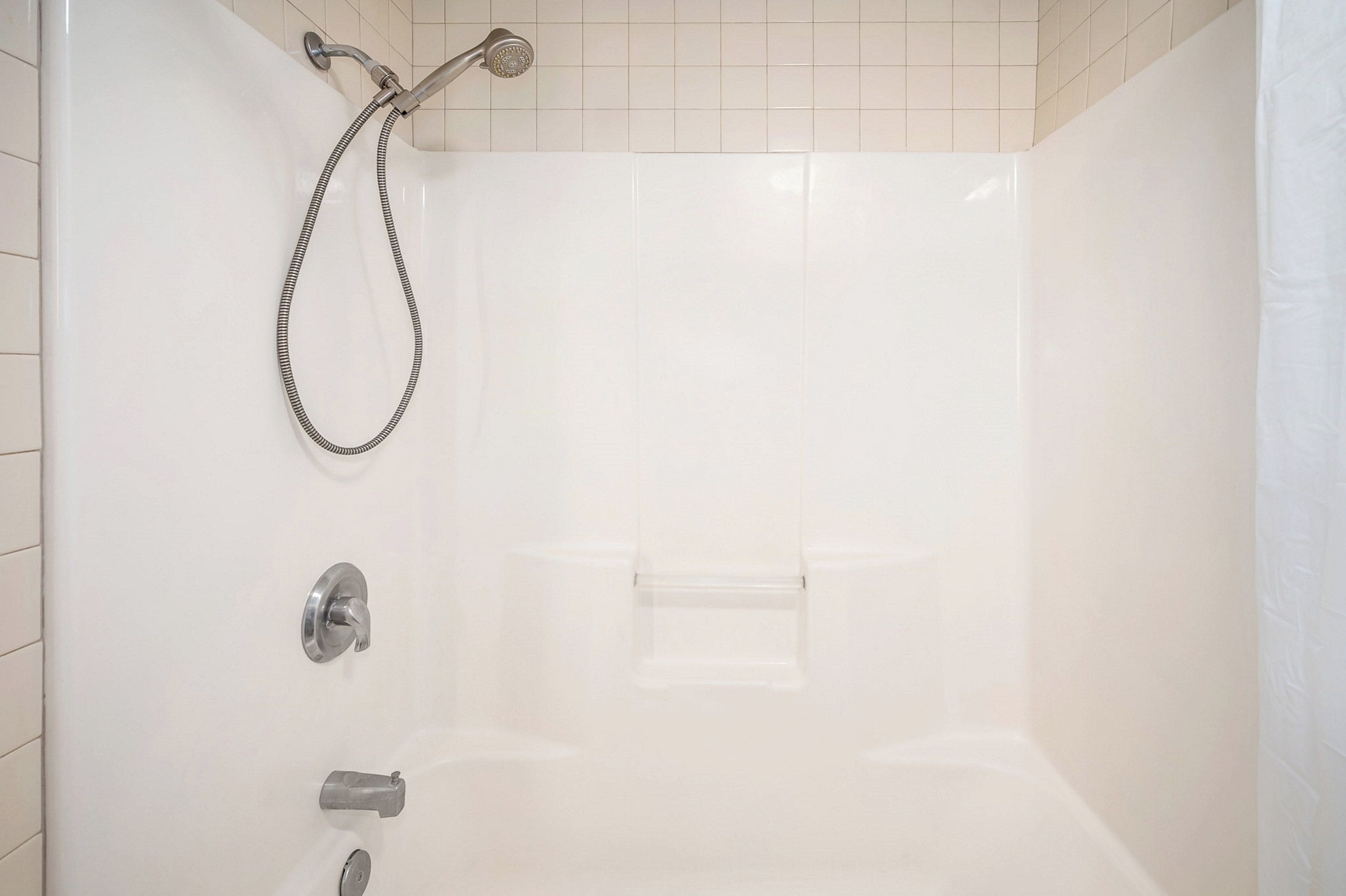 A shower with a handheld showerhead and a wall-mounted faucet.