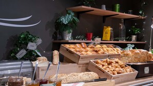 Een bakkerij display met diverse broden en gebak, potten met spreads, en een bordje met de tekst 'ibis kitchen'.