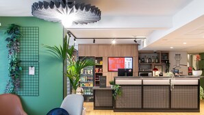 Een moderne bar met een houten toonbank, een menubord en een zithoek met een stoel en een tafel.