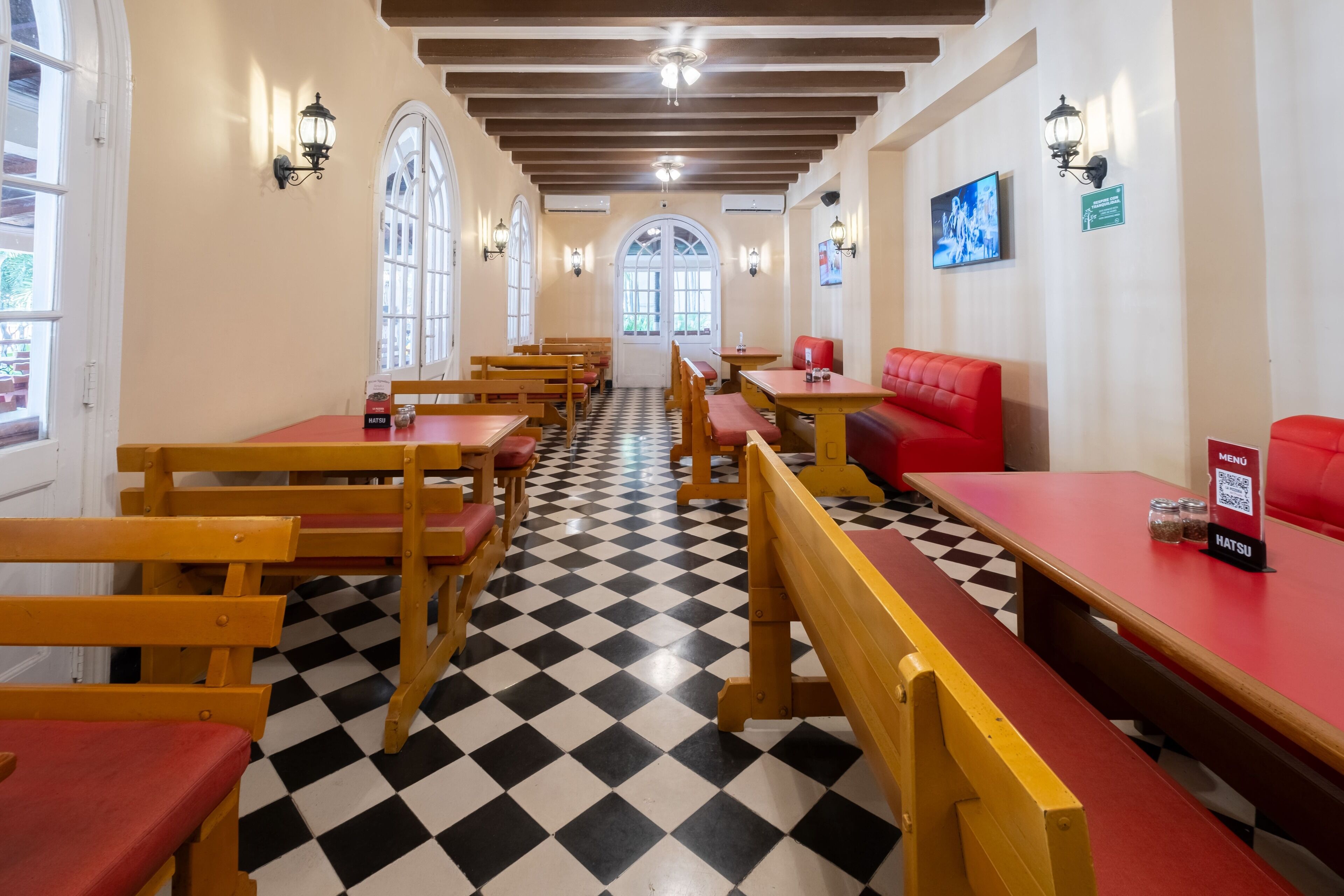 Un restaurante con piso a cuadros, bancos de madera y asientos rojos.