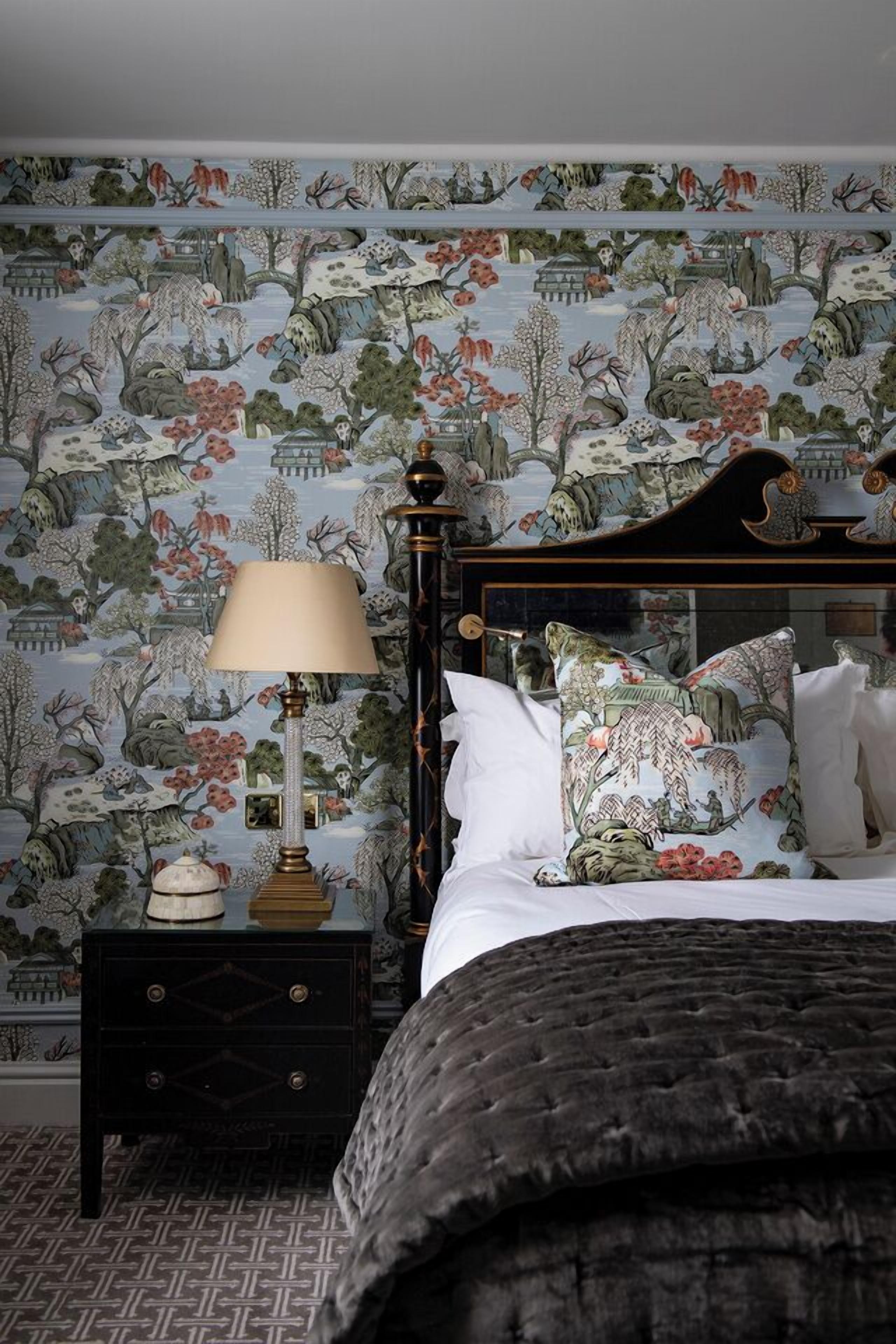 A bedroom with a bed, pillows, a nightstand, and a lamp.