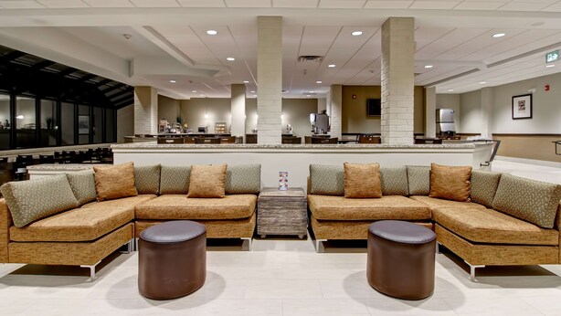 A spacious lobby with a large sectional sofa, two round ottomans, and a central coffee table. - Best Western London Airport Inn & Suites (London)