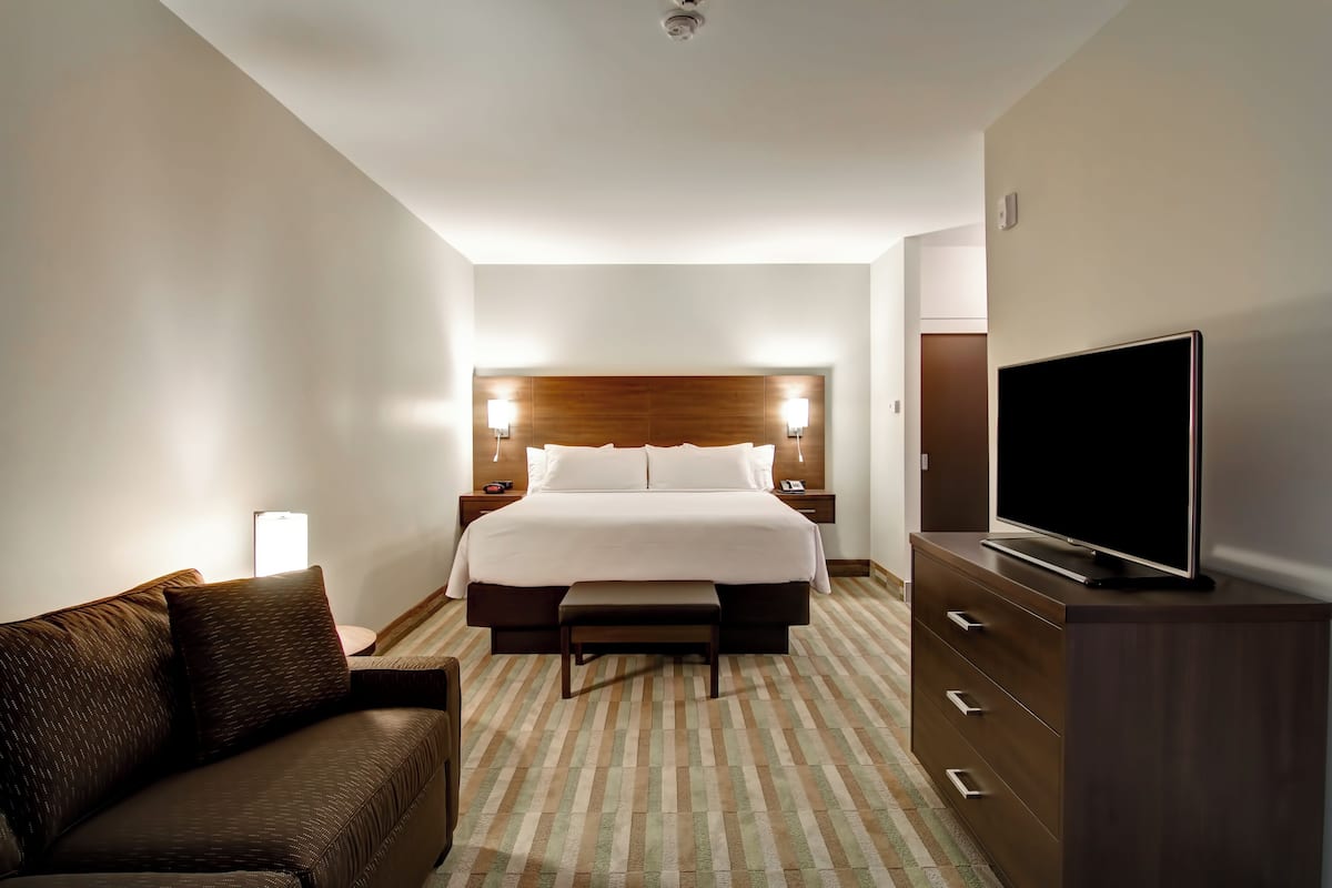 Ein Hotelzimmer mit Bett, Fernseher, Sofa und Kommode.