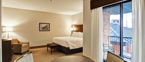 Une chambre d’hôtel équipée d’un lit, d’une table de chevet, d’une lampe, d’une chaise et offrant une vue sur l’extérieur.