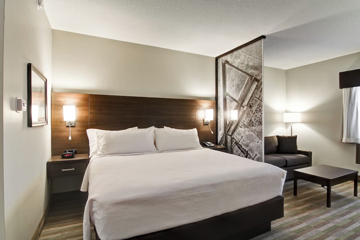 Ein Hotelzimmer mit einem großen Bett, Nachttischen, einer Sitzecke und einem kleinen Tisch.