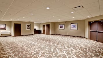 Un salón amplio alfombrado, con piso estampado, luces empotradas en el techo y cuadros enmarcados en las paredes, y una puerta a la derecha.