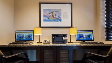 A hotel reception desk with two monitors, a printer, and a telephone.