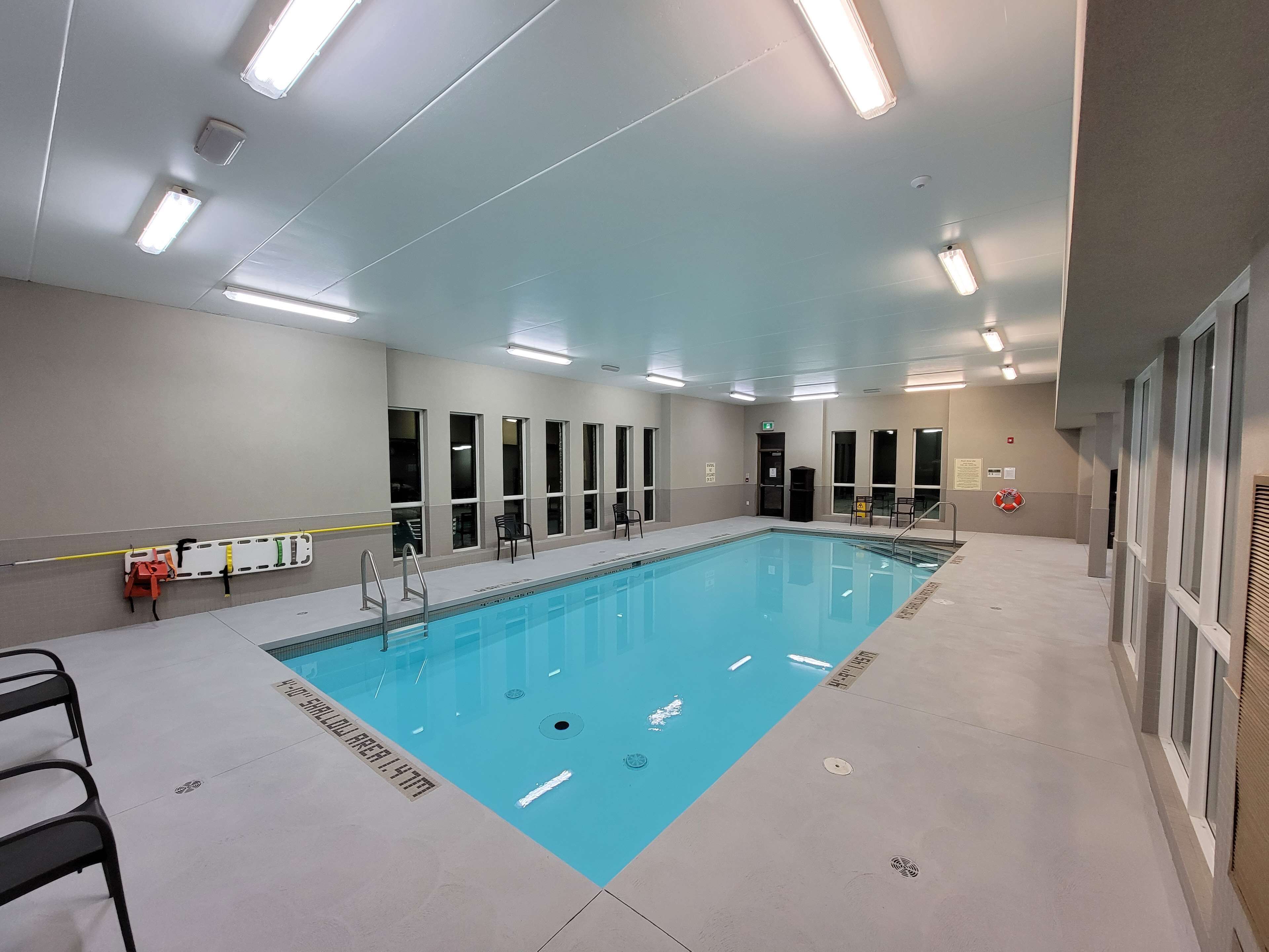 Ein großes Hallenbad mit deutlichen Fahrbahnmarkierungen, einem Rettungsschwimmerstuhl und einem Sicherheitsschild.