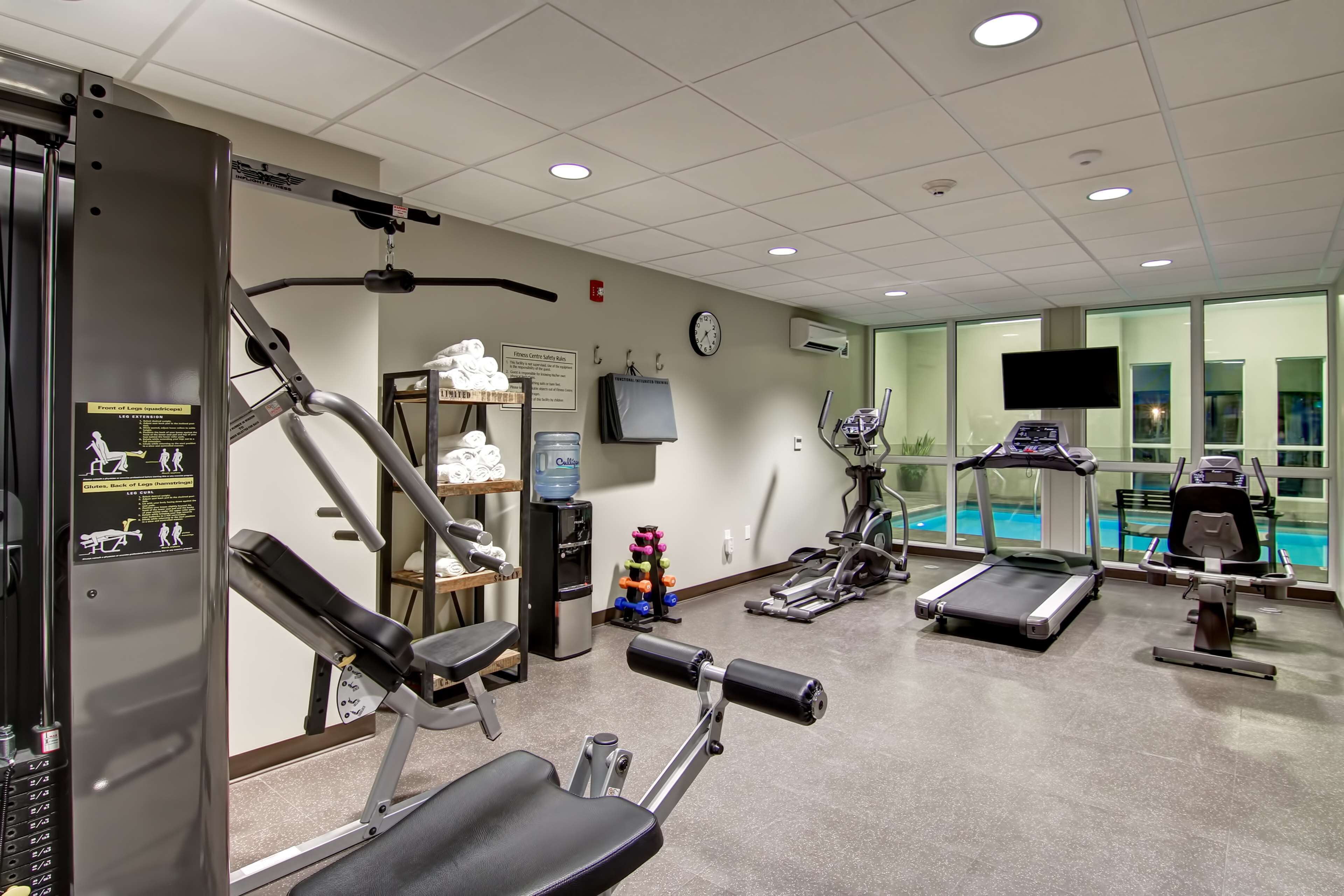 A gym with various exercise equipment, a water fountain, and a clock on the wall.