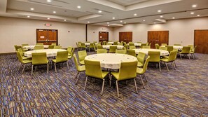 A conference room with multiple tables and chairs, carpeted floor, and doors. - Holiday Inn Express Louisville Airport Expo Center by IHG (Louisville)
