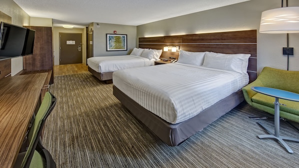 A hotel room with two beds, a TV, a desk, and a chair.
