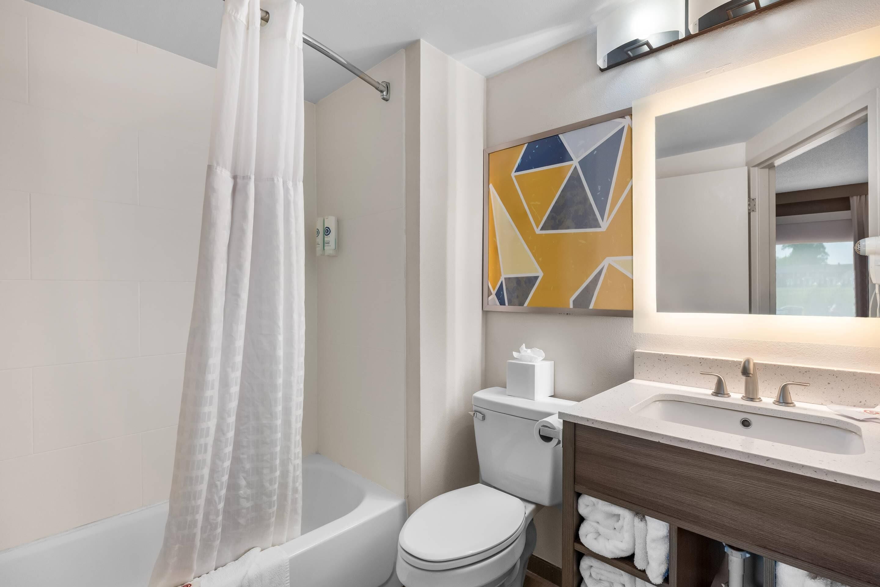 Et badeværelse med badekar, toilet og håndvask med et spejl over.