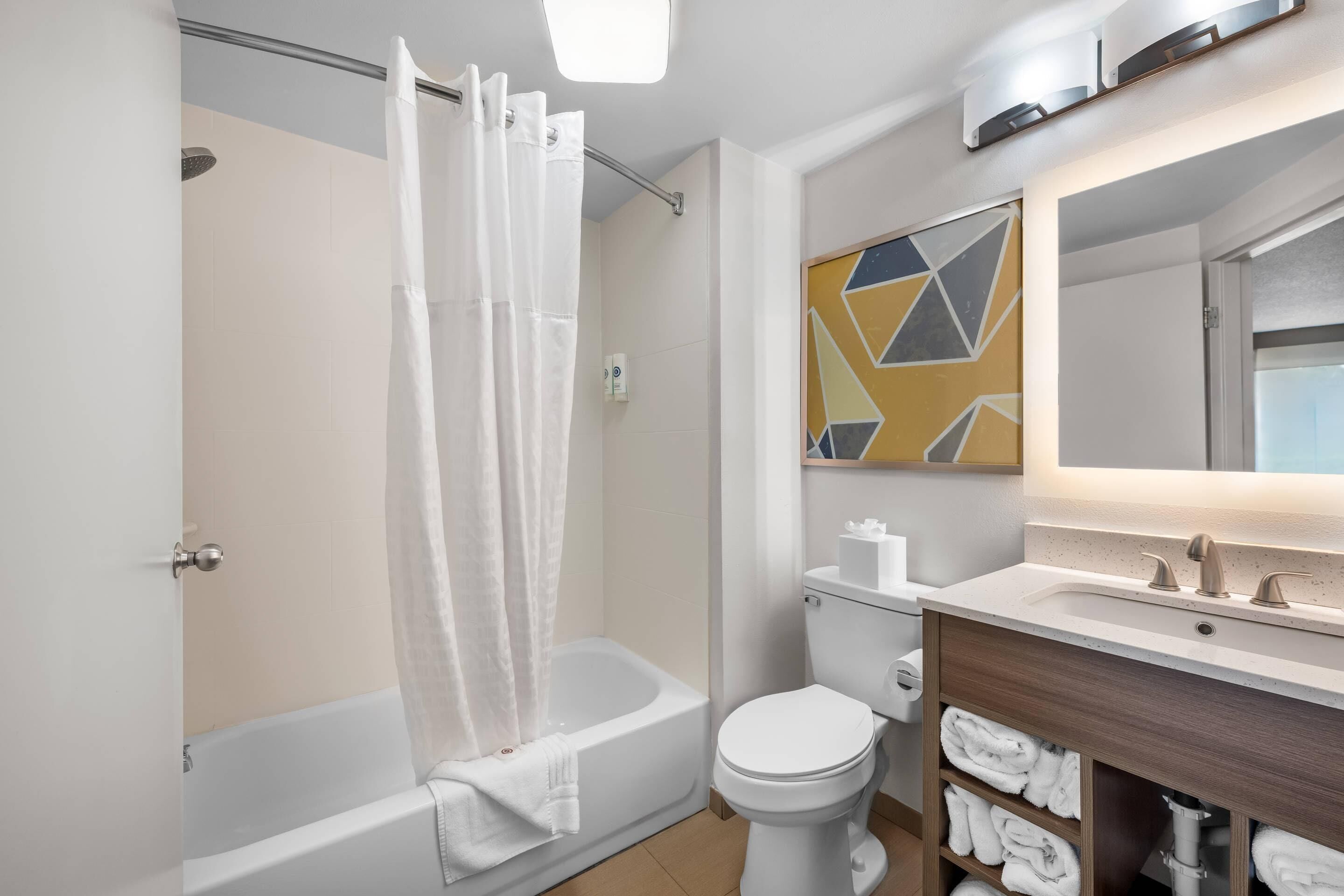 A modern bathroom with a bathtub, toilet, and vanity with a mirror.