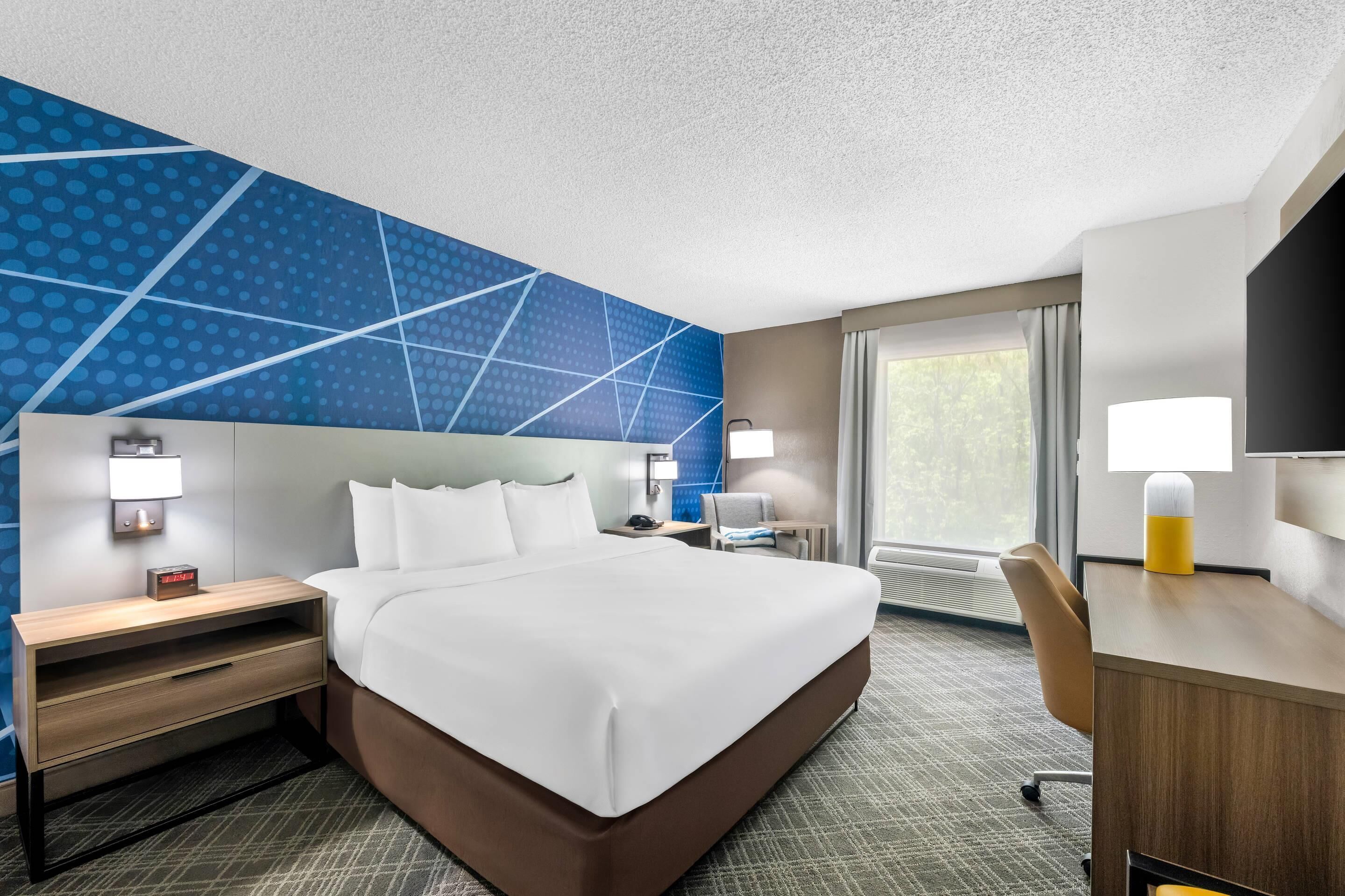 Une chambre d’hôtel avec un grand lit, des tables de chevet, un bureau et une chaise.