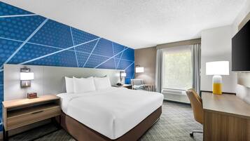 A hotel room with a large bed, bedside tables, a desk, and a chair.