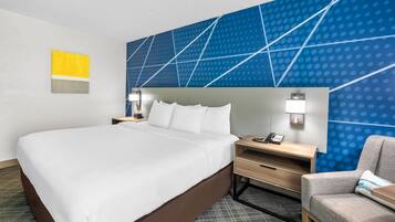 Habitación de hotel con una cama grande, un escritorio, una silla y una pared azul estampada.