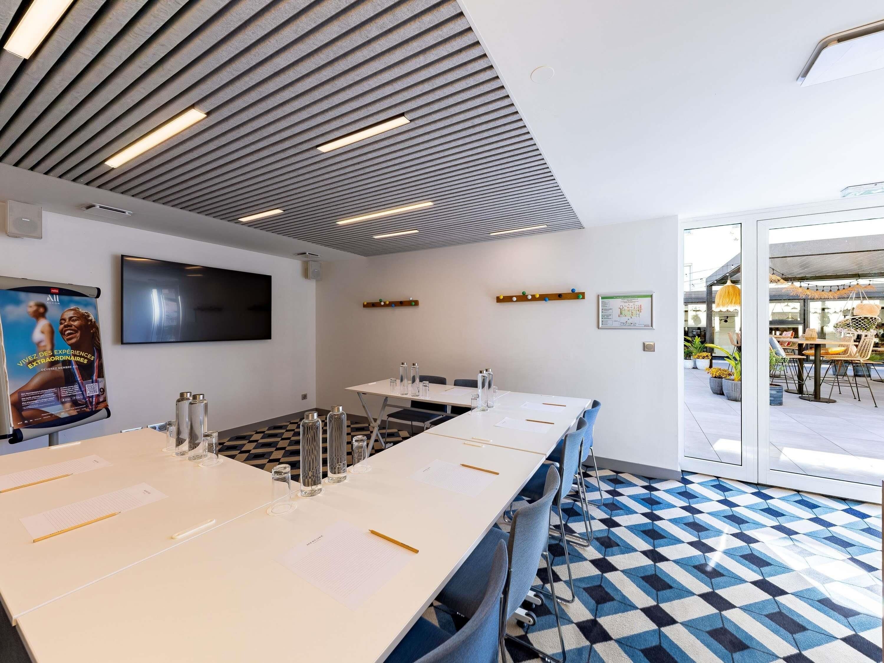 A conference room with a checkered floor, a flat-screen TV on the wall, and a poster advertising an event.