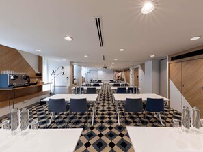 A modern conference room with tables, chairs, and a coffee station.