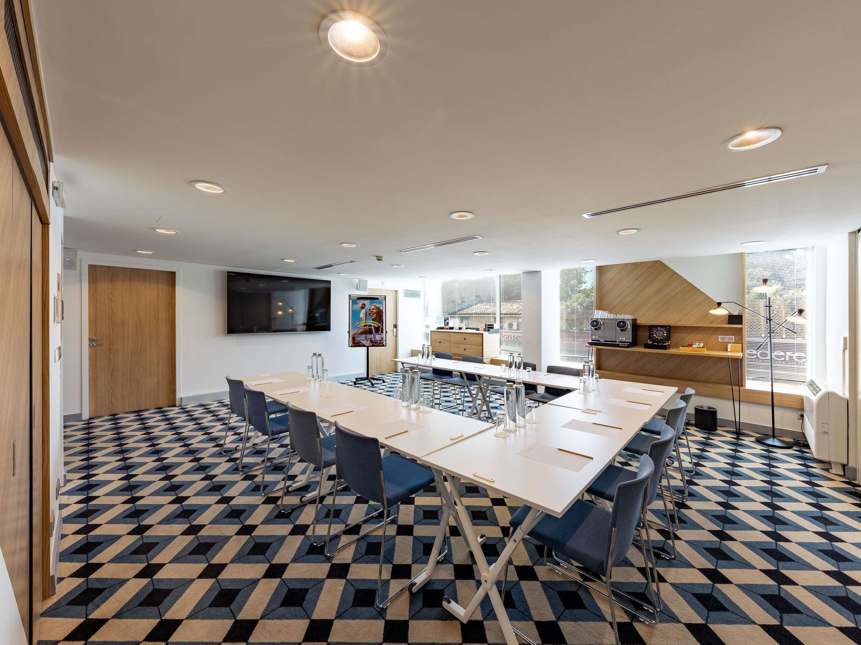 A modern conference room with a large table, chairs, and a flat-screen TV.