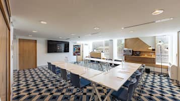 A modern conference room with a large table, chairs, and a flat-screen TV.