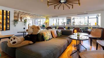 Ein stilvoller Aufenthaltsraum mit einer großen Couch, einem Teddybären und einer außergewöhnlichen Deckenleuchte.