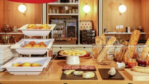 Un bufé de desayuno con diversos pasteles, pan y embutidos.