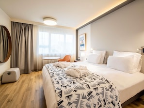 A hotel room with a bed, a round table, a chair, a desk with a lamp, and a wall-mounted light fixture. - Mercure Marseille Centre Prado Vélodrome (Marseille)