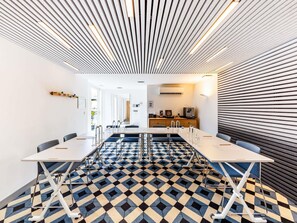 Een moderne vergaderzaal met een vloer met een geometrisch patroon, witte tafels en stoelen.