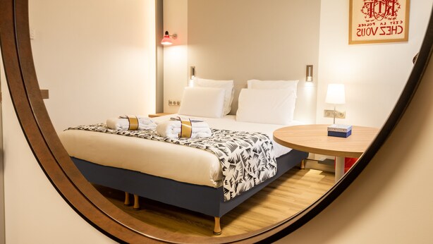 Una habitación de hotel moderna con cama, mesita de noche y un cartel en la pared.