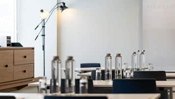A modern hotel room with a desk, chairs, a lamp, and a minibar.