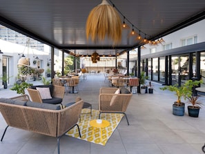 An outdoor seating area with wicker furniture, hanging lights, and potted plants. - Mercure Marseille Centre Prado Vélodrome (Marseille)