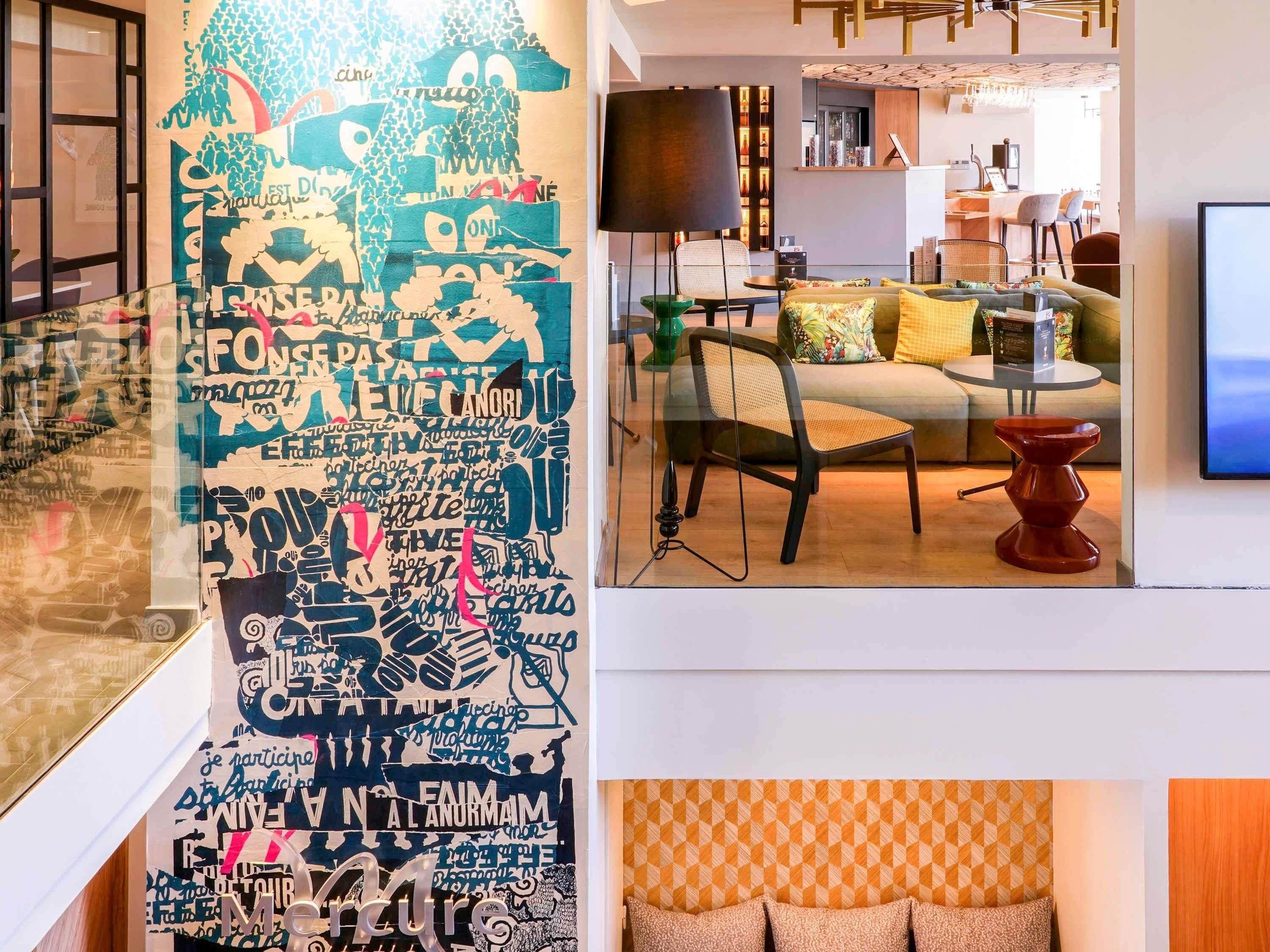 A modern interior with a large wall of text art, a sofa, a TV, and a dining area.
