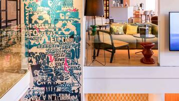 A modern interior with a large wall of text art, a sofa, a TV, and a dining area.