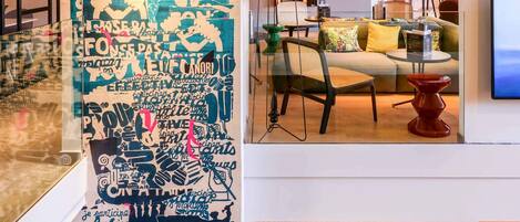 A modern interior with a large wall of text art, a sofa, a TV, and a dining area.