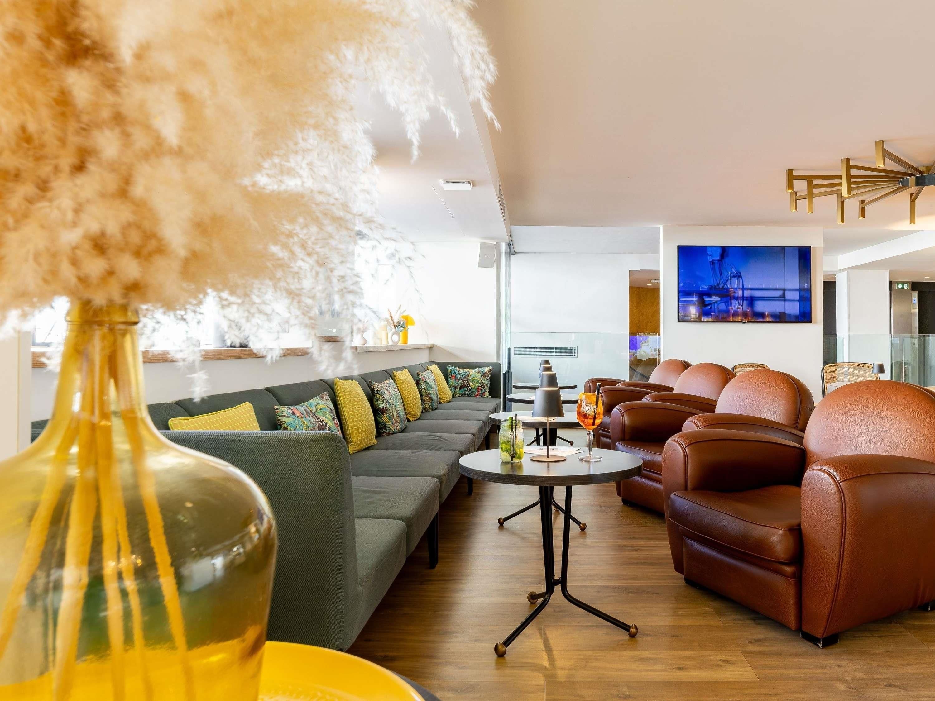 Een moderne woonkamer met een bank, een bijzettafeltje en leren fauteuils.