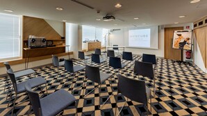Un salón de conferencias con piso a cuadros, una pantalla de proyección y una pared de acento de madera.