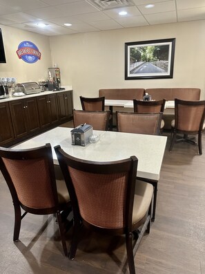 A breakfast corner with a buffet, seating area, and a framed picture on the wall. - Rodeway Inn (Lynchburg)