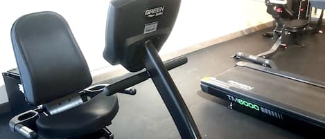 Een stilstaande fiets, een loopband en een aan de muur bevestigde televisie in een sportschool.