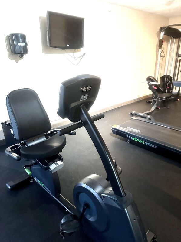 A stationary bike, a treadmill, and a wall-mounted TV in a gym.