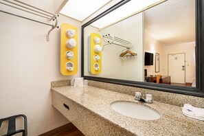 A bathroom with a granite countertop, a sink, a mirror, and towel dispensers. - Motel 6 Covington, TN (Covington)