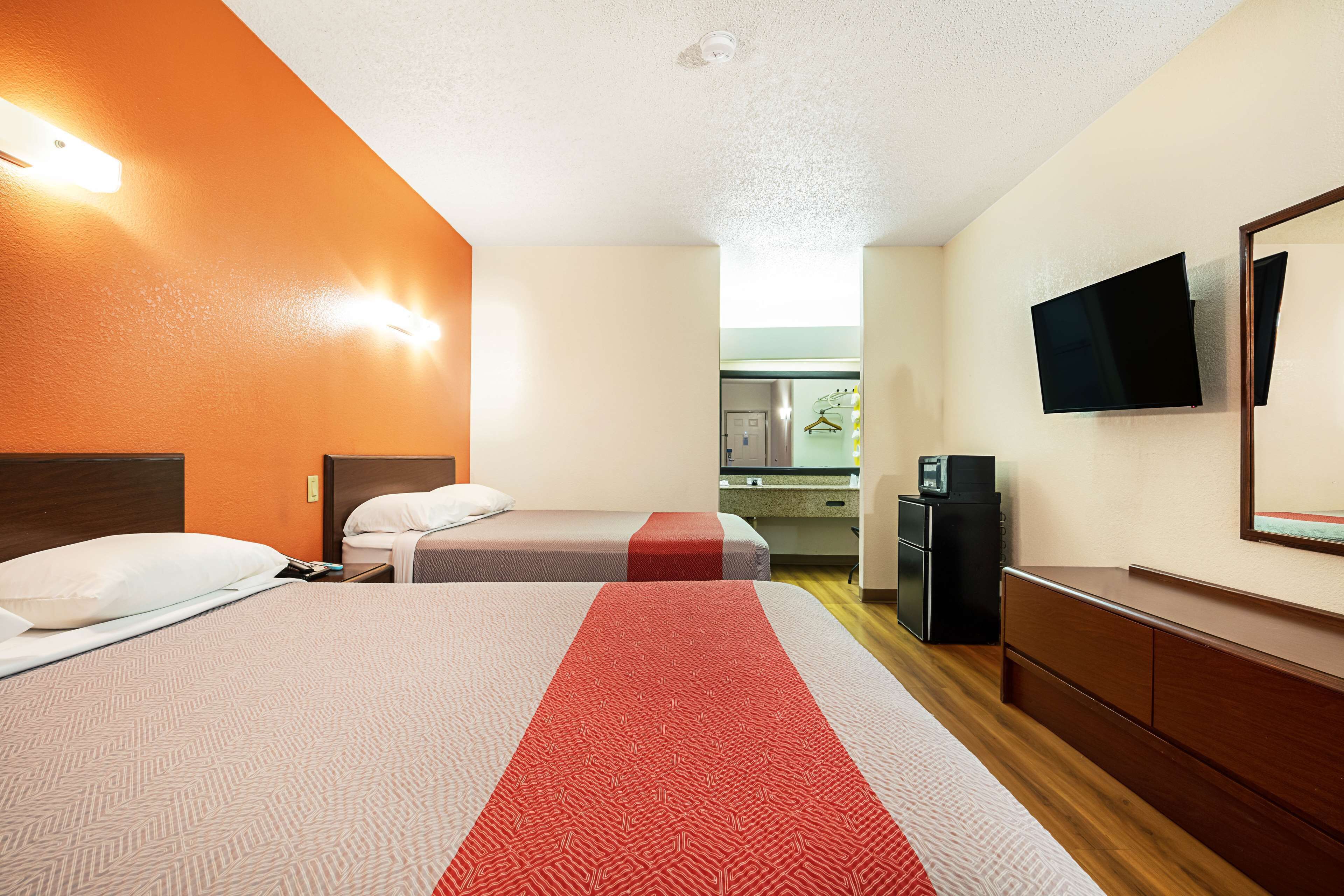 Una habitación de hotel con dos camas, televisión, escritorio y kitchenette.