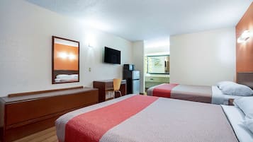 Una habitación de hotel con dos camas, un escritorio, una silla, un televisor y un espejo.