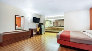 A hotel room with a bed, a desk, a chair, a television, and a kitchenette. - Motel 6 Covington, TN (Covington)