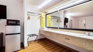 A modern bathroom with a large mirror, a sink, and a microwave. - Motel 6 Covington, TN (Covington)