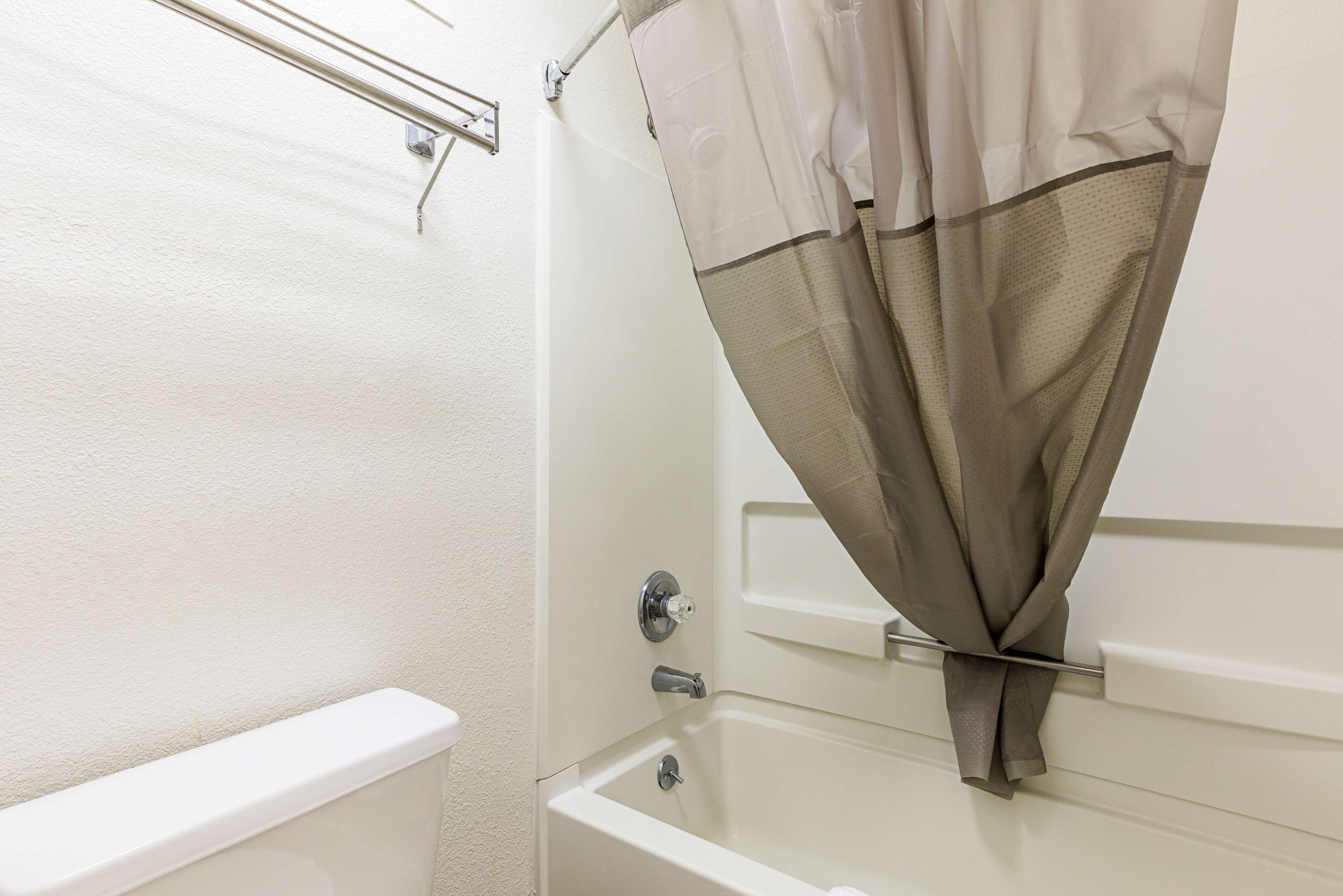 Un baño con bañera, cortina de ducha y toallero.