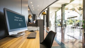 Een moderne hotellobby met een groot scherm waarop staat: 'Open up your world' en 'IHG Rewards'.