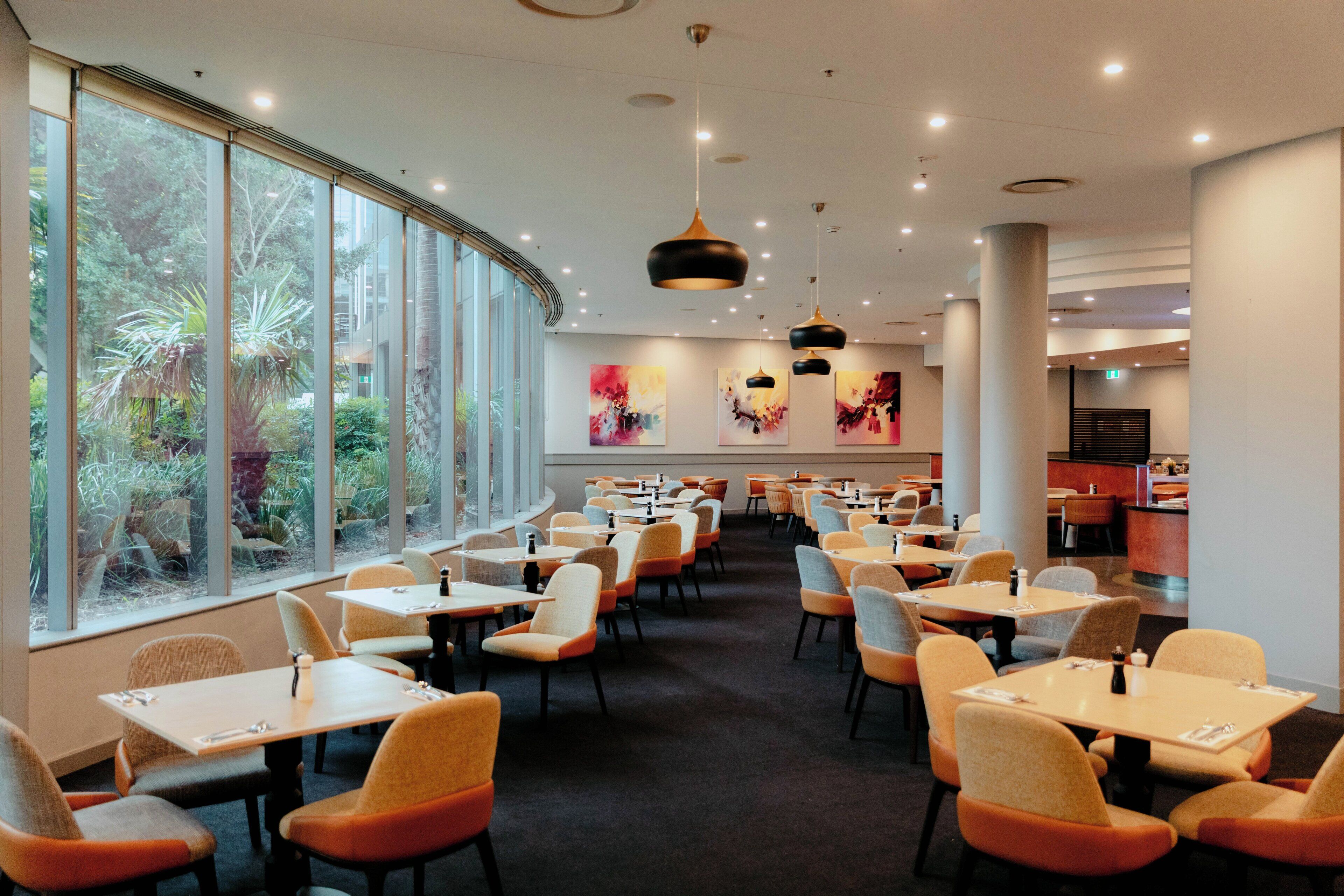 Un restaurante moderno con una barra larga, varias mesas y sillas.
