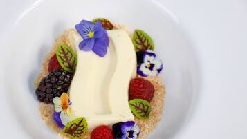 A dessert with various fruits and leaves on a white plate.